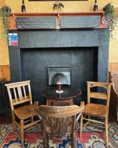 Inside the Free Trade Inn: fireplace, chairs and a half pint